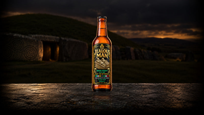 The Jealous Man Irish stout bottle before an ancient passage tomb at dusk